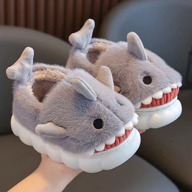 Chaussons pour enfants en forme de requin, couleur grise, avec peluche douce et confortable. Dotés de nageoires latérales et de dents blanches amusantes, ils apportent un style unique et ludique. Parfaits pour garder les pieds au chaud tout en ajoutant une touche de fantaisie.

